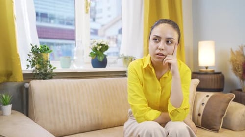 Woman Sitting Pensively on Couch in Living Room