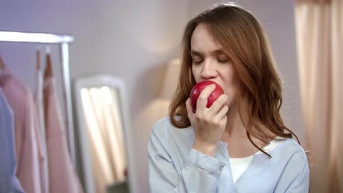 Smiling Woman Bites into a Red Apple