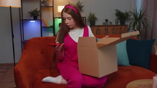 Young Adult Opens Package and Uses Phone Indoors
