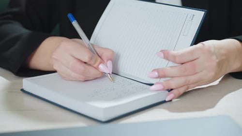 Close Up Woman Writing Note in Diary at Office Desk