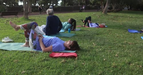 Multiracial senior people doing yoga exercises outdoor with city park in background