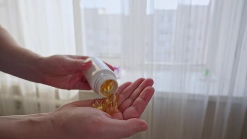 Person Pouring Omega 3 Vitamin d Capsules Into Hand