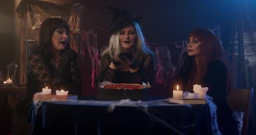 Women Dressed as Witches Eating Pizza at Table