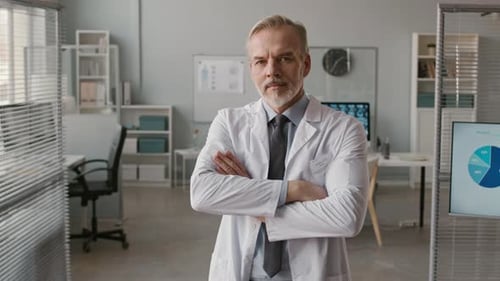 Portrait of Adult Male Doctor Posing with Hands Folded in Office