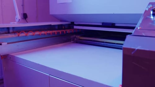 Technician preparing screen printing machine for operation in workshop