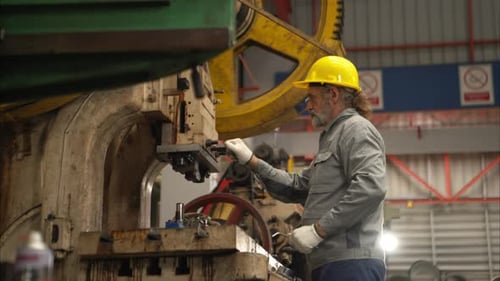 Senior experienced technician checking and maintenance a large machine in metal sheet factory