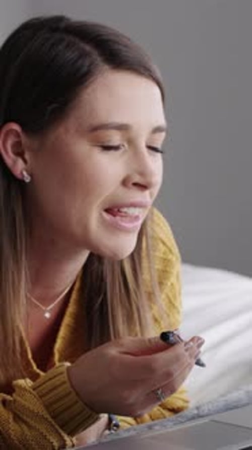 Smiling Woman Writing in Bed with Laptop