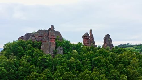 Belogradchik sandstone rock formations rise above Bulgarian forest landscape, drone shot