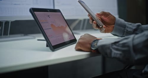 Stock Trader Monitoring RealTime Stocks Exchange Market Charts on Smartphone and Digital Tablet