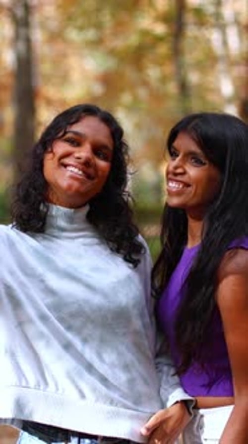 Zwei fröhliche indische Schwestern machen ein Selfie in einem Herbstpark
