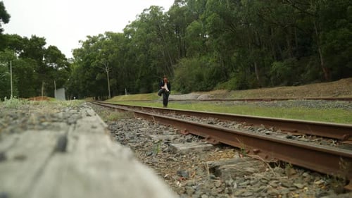 A traveling hobo walks the railway line along an abandoned train station.