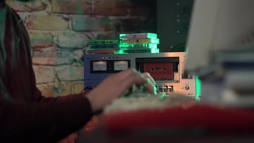 Cinta de audio que suena en la cubierta mientras un hombre escribe en el teclado de una computadora de escritorio de la década de 1980