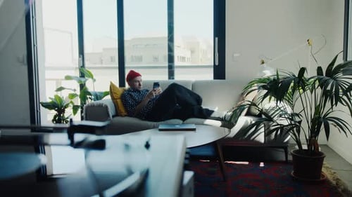 Young Adult Relaxing at Home with Smartphone