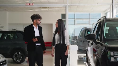 Man and Woman Discuss Cars in Dealership Showroom