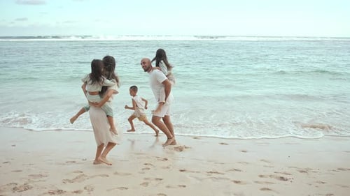 Happy Family of Adult People with Young Children at Sea Water of Ocean Beach