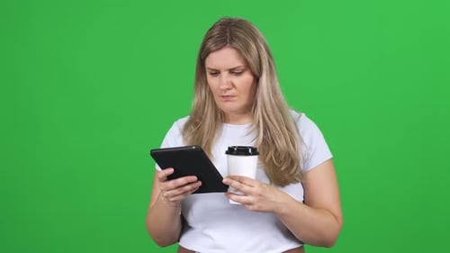 Woman Standing on Chromakey Background Using Screen Tablet and Drinks Coffee Texting and Surfing the