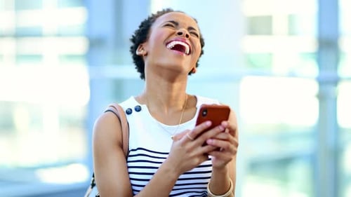 Woman Laughing While Using Phone in Bright Building