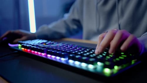 Computertastatur mit bunten Lichtern und Händen eines Gamer-Streamers, der ein Online-Videospiel spielt