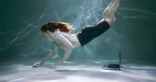 Schöne junge Geschäftsfrau taucht, um Laptop und Smartphone aus dem Wasser zu holen