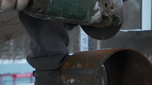 Mann schneidet Metallrohr mit Kreissägeclip, Funken fliegen von heißem Metall, Mann hart arbeitend