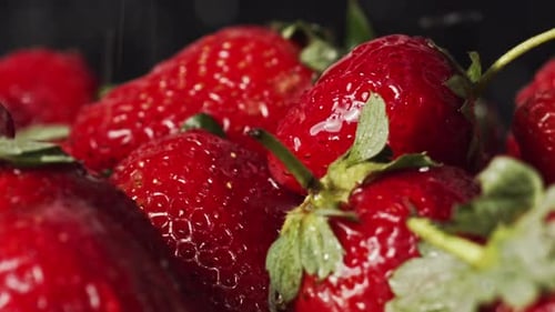 Water droplets splashing onto red strawberries. Macro closeup