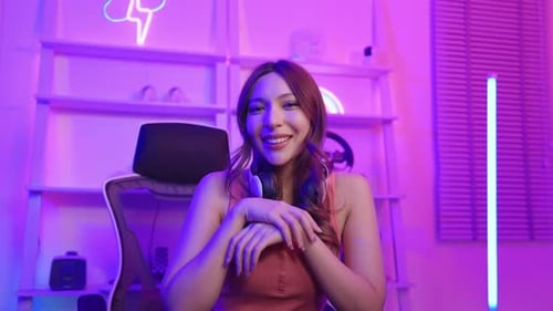 Woman Removing Headphones in Room with Neon Lighting