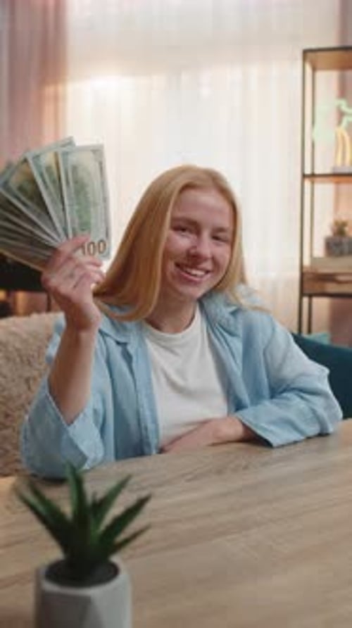 Woman Celebrates Counting Money at Table Indoors