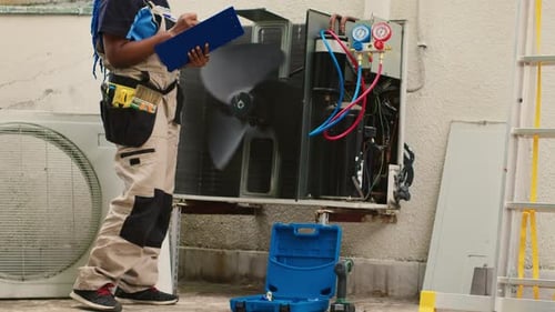 HVAC Technician Inspecting Air Conditioning Unit and Taking Notes