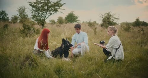 Young Adults with Dog in a Grassy Field