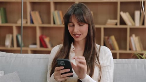 Woman Smiles Using Phone Indoors