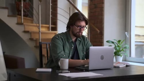 Young Businessman Working with Laptop and Smiling While Sitting at Table in Home Office Spbas