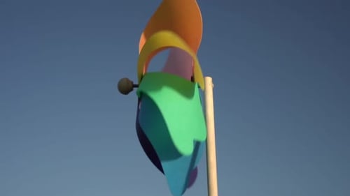 Multicolored Toy Windmill Against the Background of the Sky and the Sun