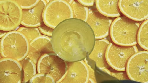 Pouring Citrus Juice into Glass with Orange Slices