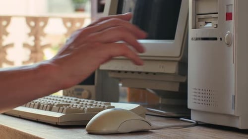 Hombre trabajando y jugando en una computadora retro, ingeniero de TI con una computadora antigua en casa usando una vieja