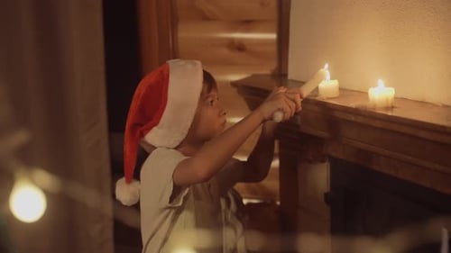 Child in Santa Hat Lighting Candle for Christmas