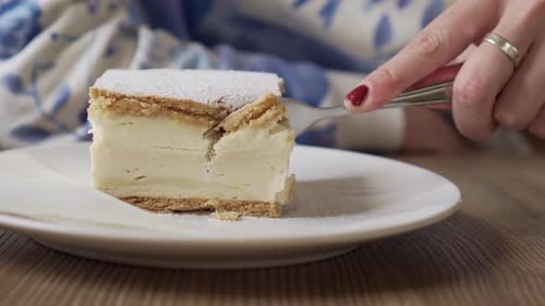 Flaky Cream Cake with Powdered Sugar Being Eaten