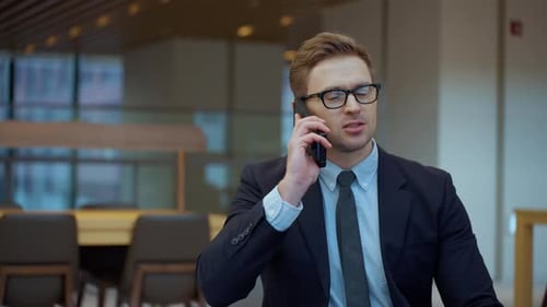 Cheerful businessman young man in an office making a phone call