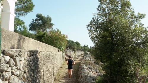 Healthy And Fit Man Running On Narrow Mountain Trail With Dog. - aerial follow