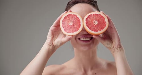 Smiling Woman Posing with Grapefruit Halves