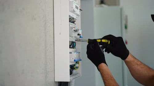 Technical Electrician Fixing the Cable Into the Terminal of a Circuit Breaker of a Electrical Panel