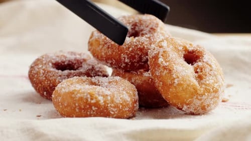 Traditionelle spanische Donuts mit bunten Streuseln, Nahaufnahme von rosafarbenen Süßigkeiten, Lebensmittelmakro