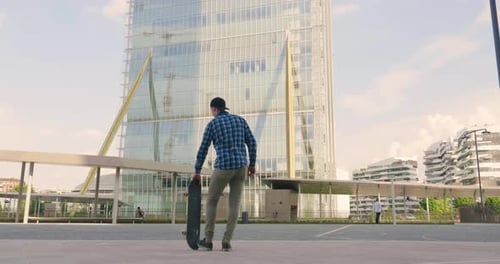 Portrait a boy practices skateboarding in the middle of the city, between buildings and skyscraper