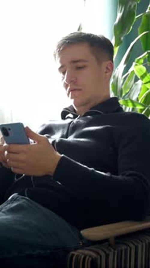 Man Uses Smart Phone While Sitting in Chair