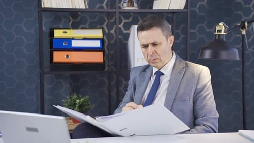 Serious and focused mature businessman looking at paperwork files in office.