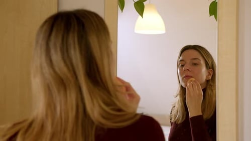 Woman Applying Makeup in Front of Mirror