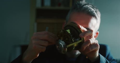 Slow motion close up of a professional watchmaker repairer working on a vintage mechanism clock in