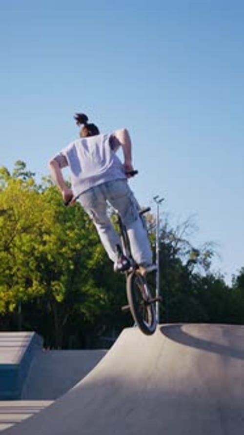 Young Man Riding Bike and Jumping at Skatepark