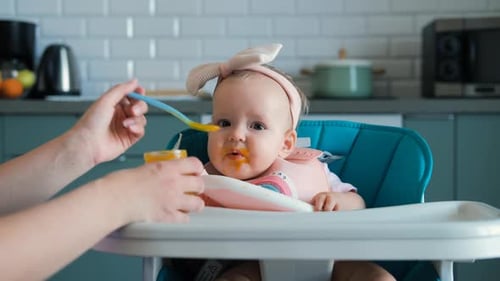 Adorable Infant Being Fed in High Chair