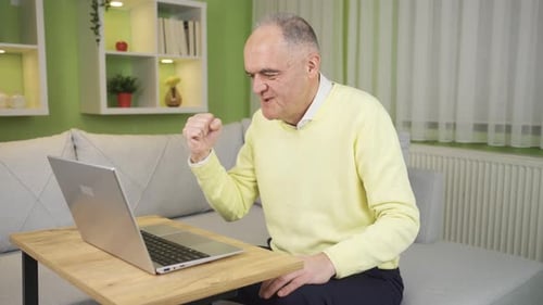 Happy old man is happy to do his work on laptop at home in an easy and practical way.