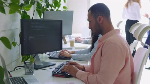 Multi Ethnic Computer Programmer Writing a Code in an Office